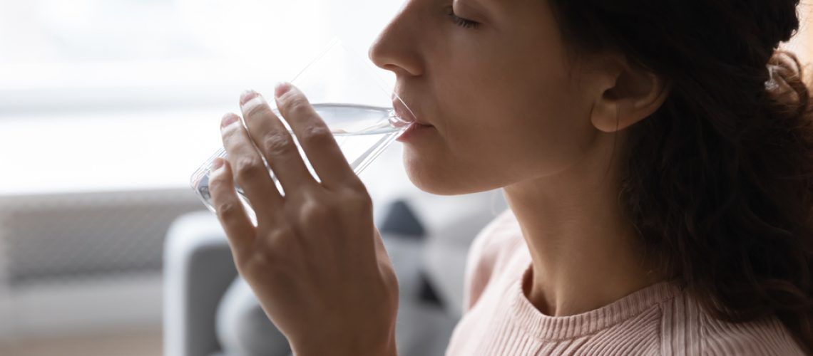 Woman,Hold,Glass,Makes,Sip,Of,Still,Water,,Close,Up